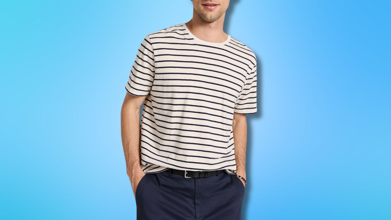 close-up of a man wearing a white and navy striped t-shirt with his hands in the pockets of his dark trousers