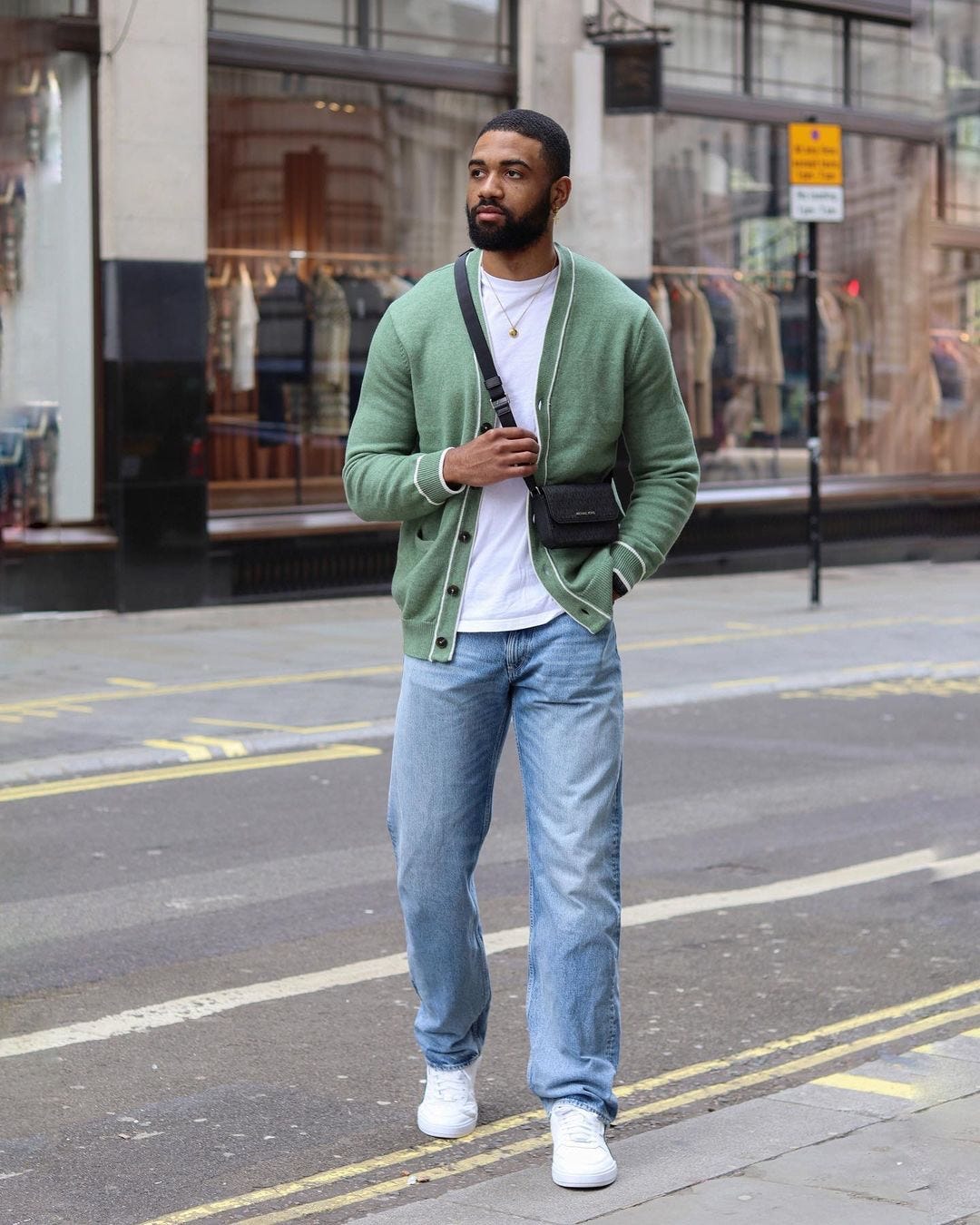 man in green cardigan and light wash jeans
