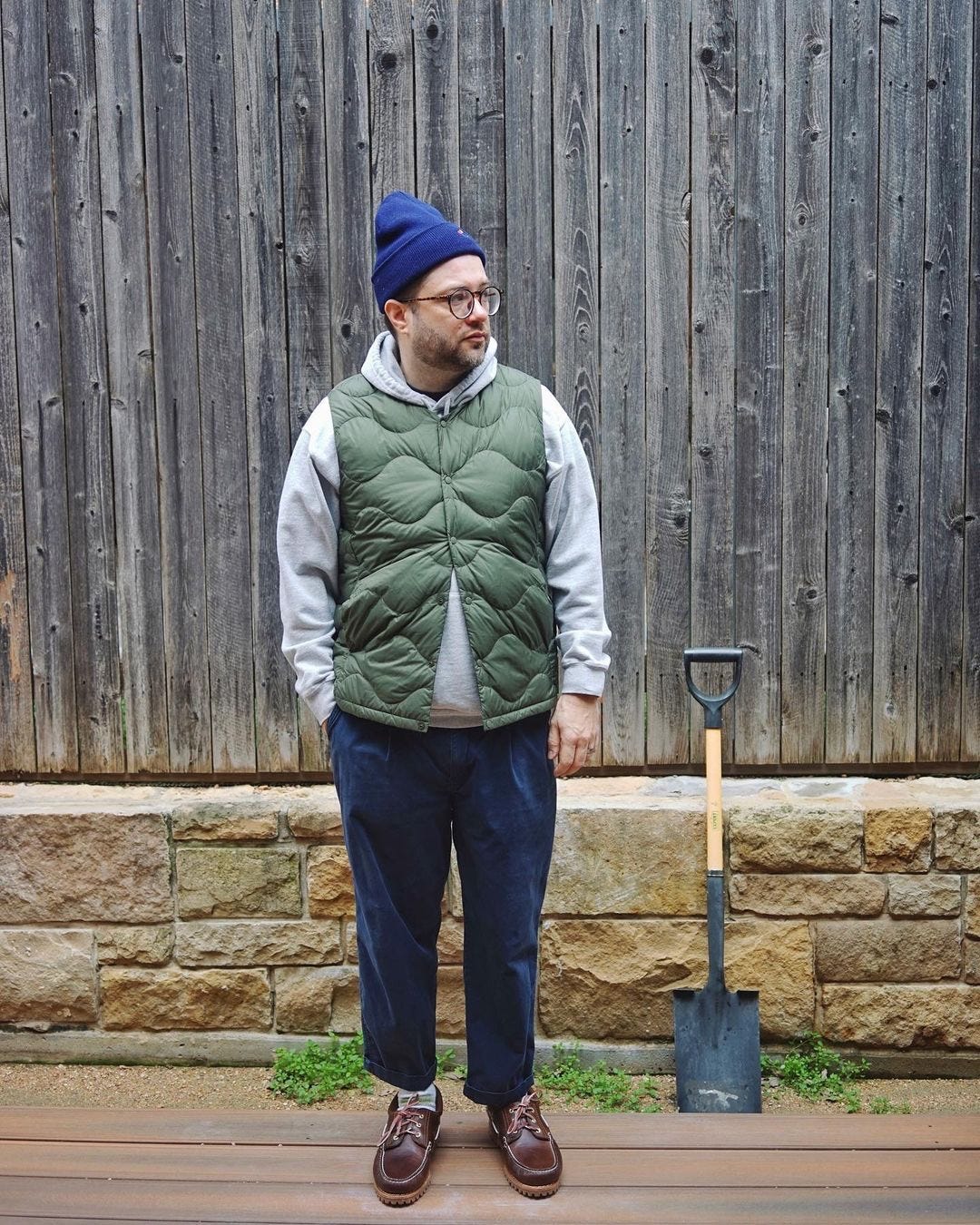 man in hoodie sweatshirt with green quilted vest and navy beanie