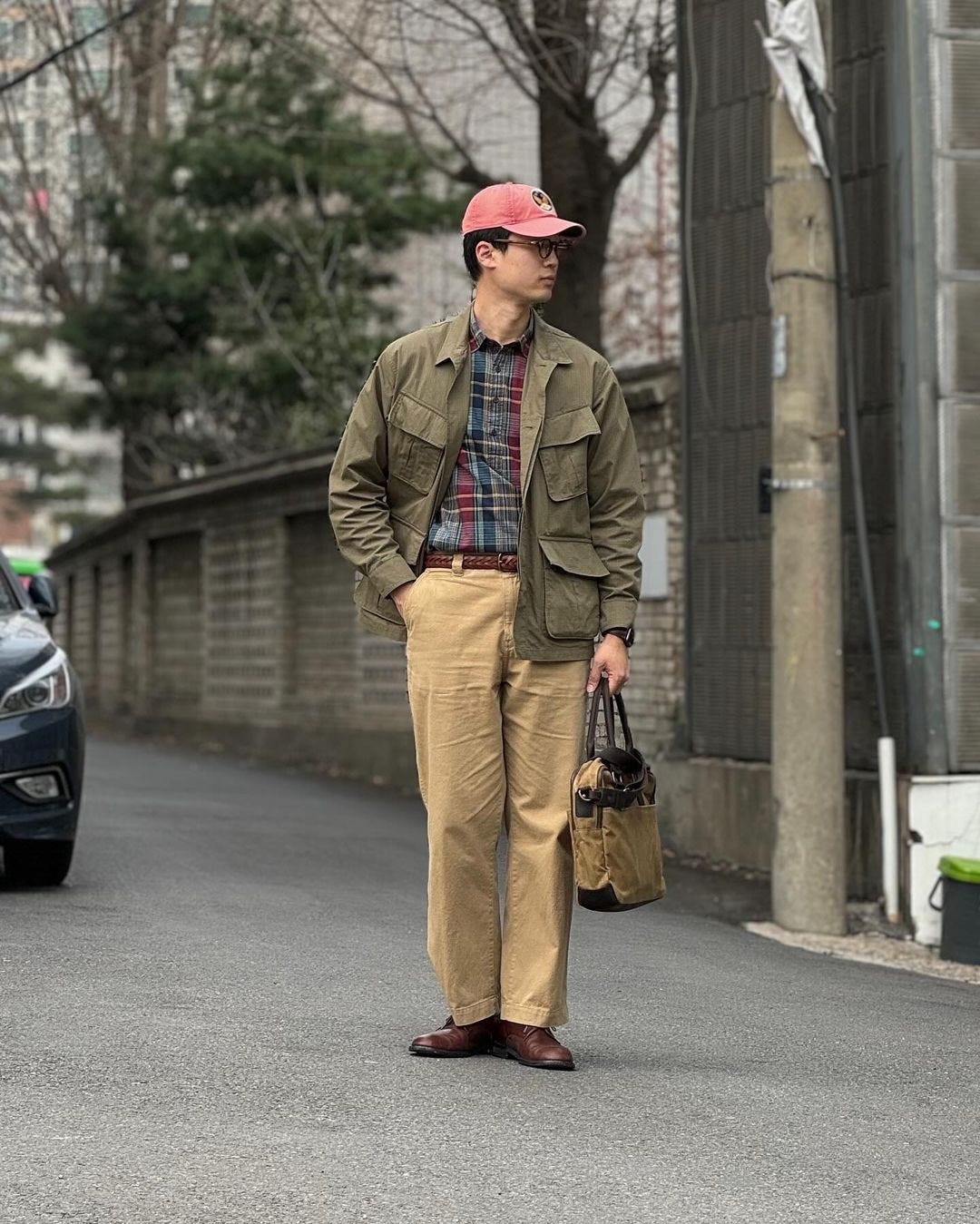 man wearing a plaid shirt with tan trousers and an olive green jacket