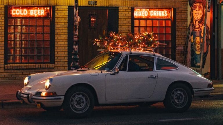 vintage car with a lit-up christmas tree on the top in front of a bar