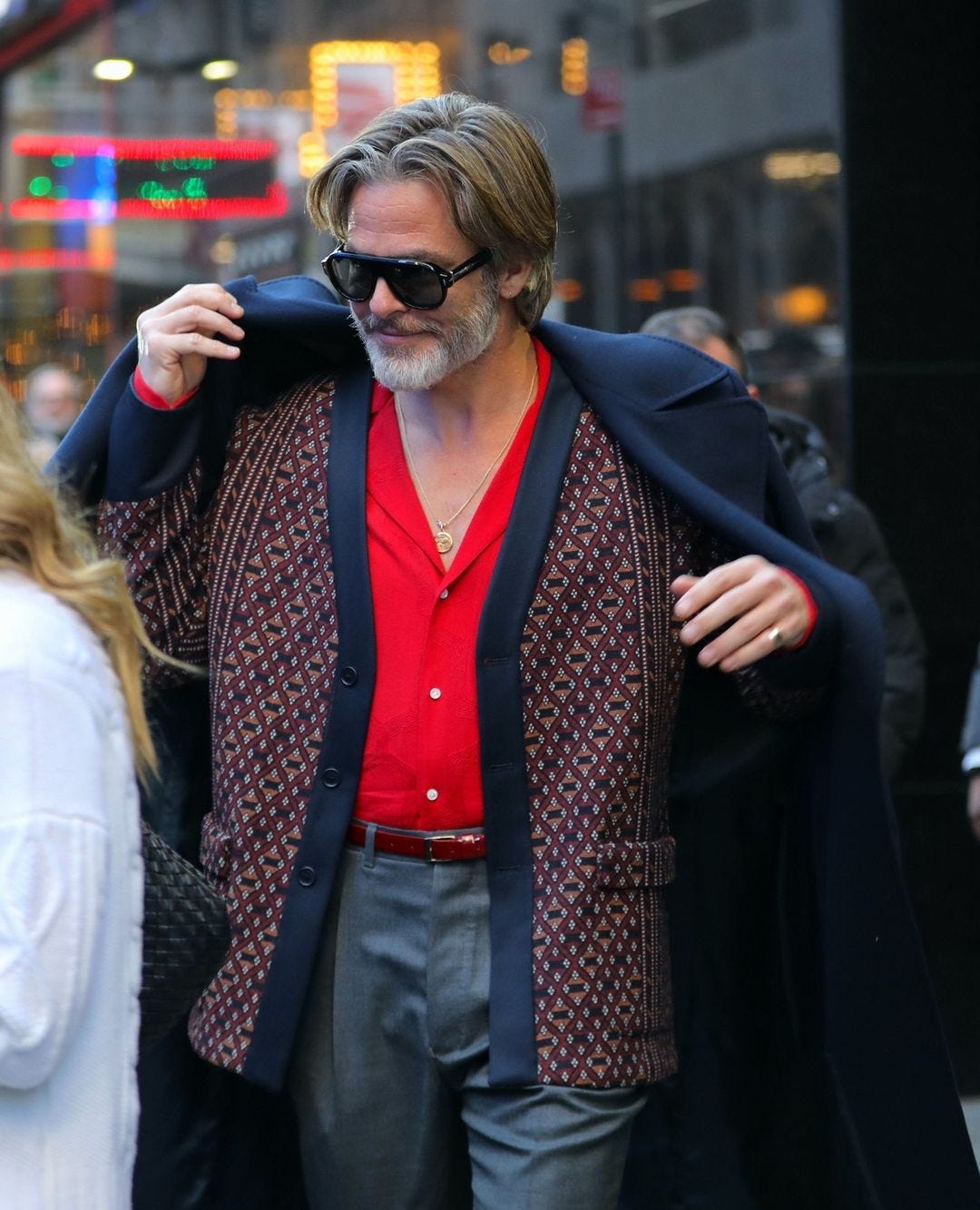 Chris Pine wearing a red button-down shirt and navy and red cardigan
