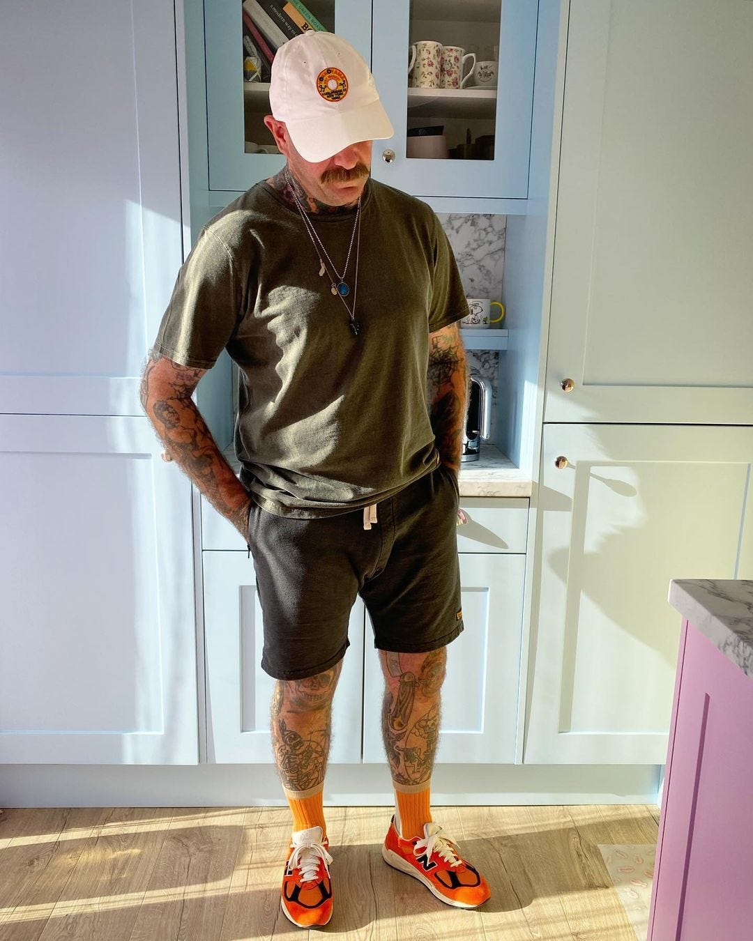 Man wearing high socks and shorts standing in kitchen
