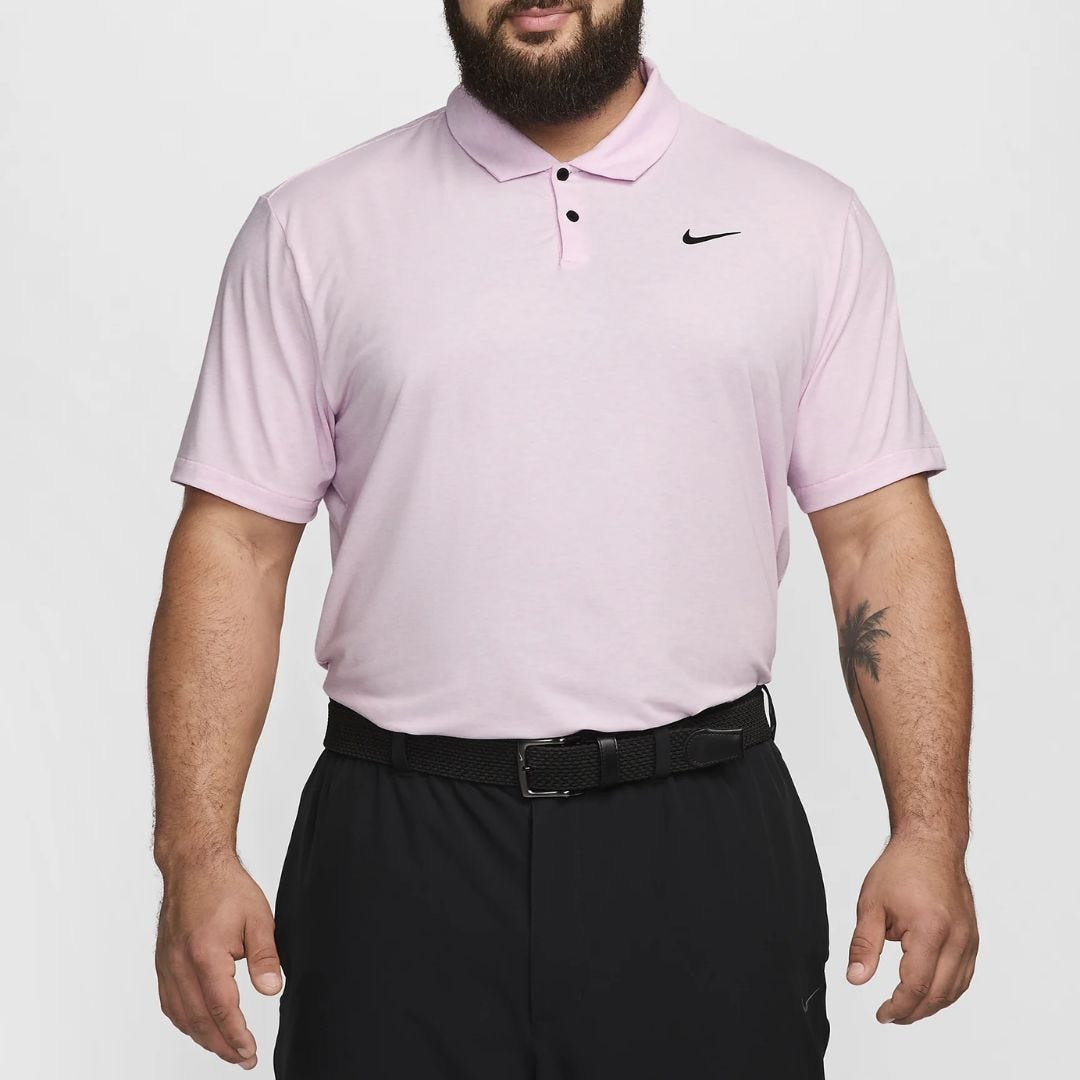 torso of man wearing light pink nike golf polo shirt and black pants