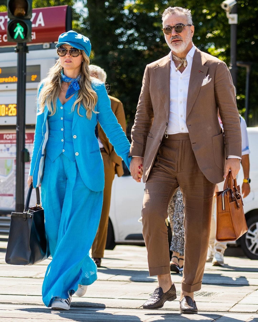 Chic man and woman holding hands, both wearing casual suits