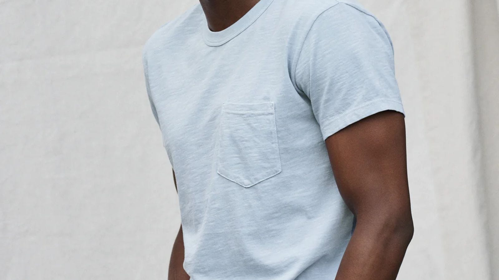 up-close image of man from the neck to the waist, wearing a light blue pocket t-shirt