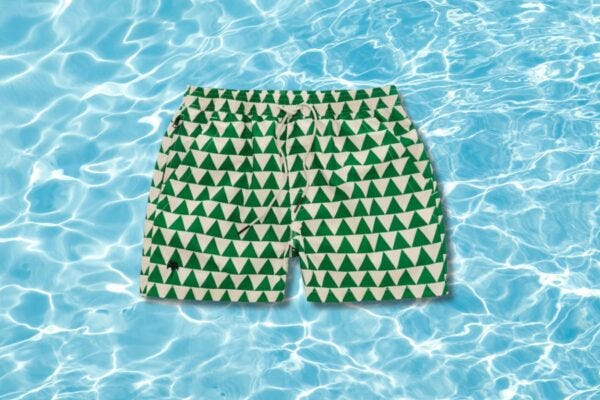image of green and white men's swim trunks set against a pool water background