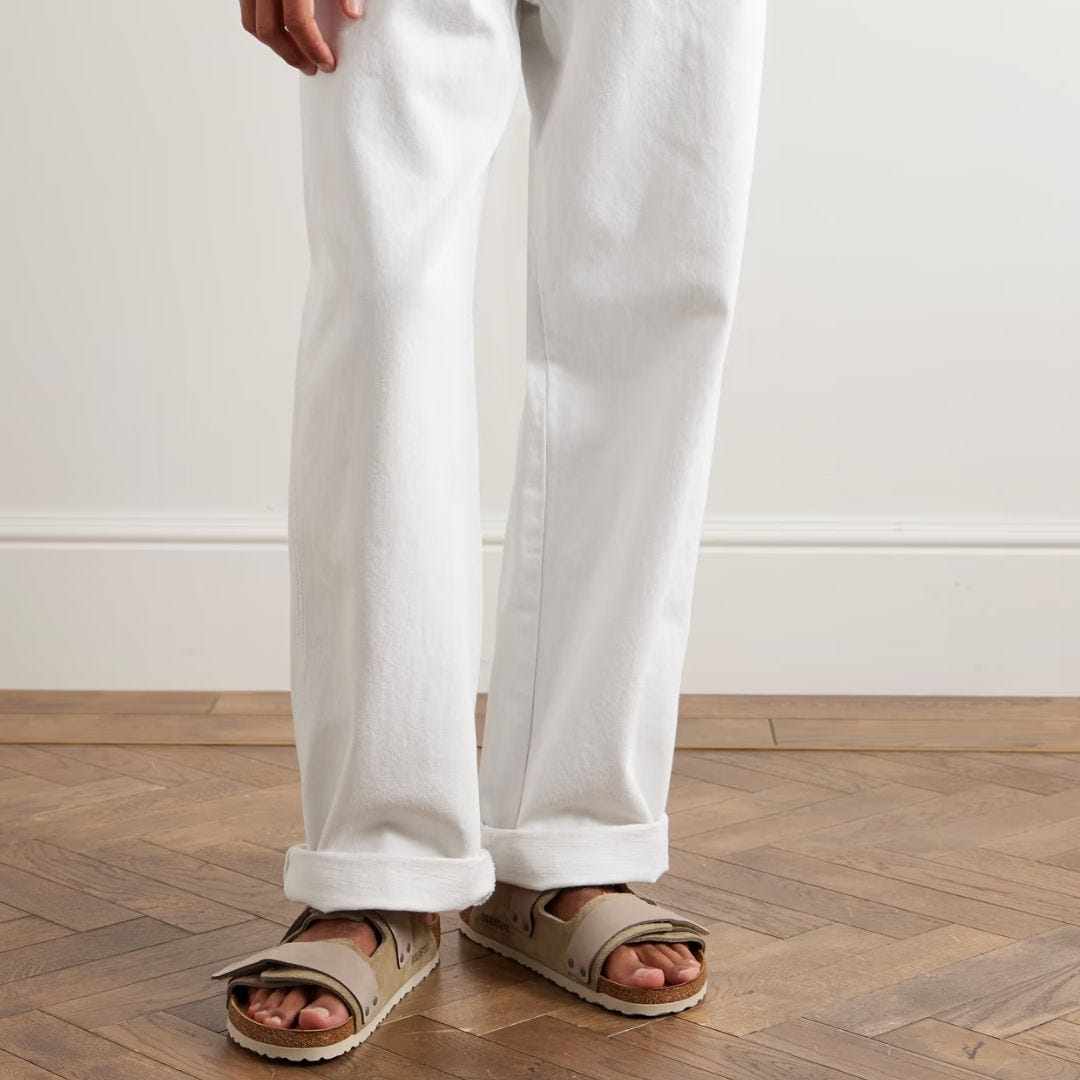 image of man from the legs down wearing white cuffed pants with light brown suede slip-on sandals