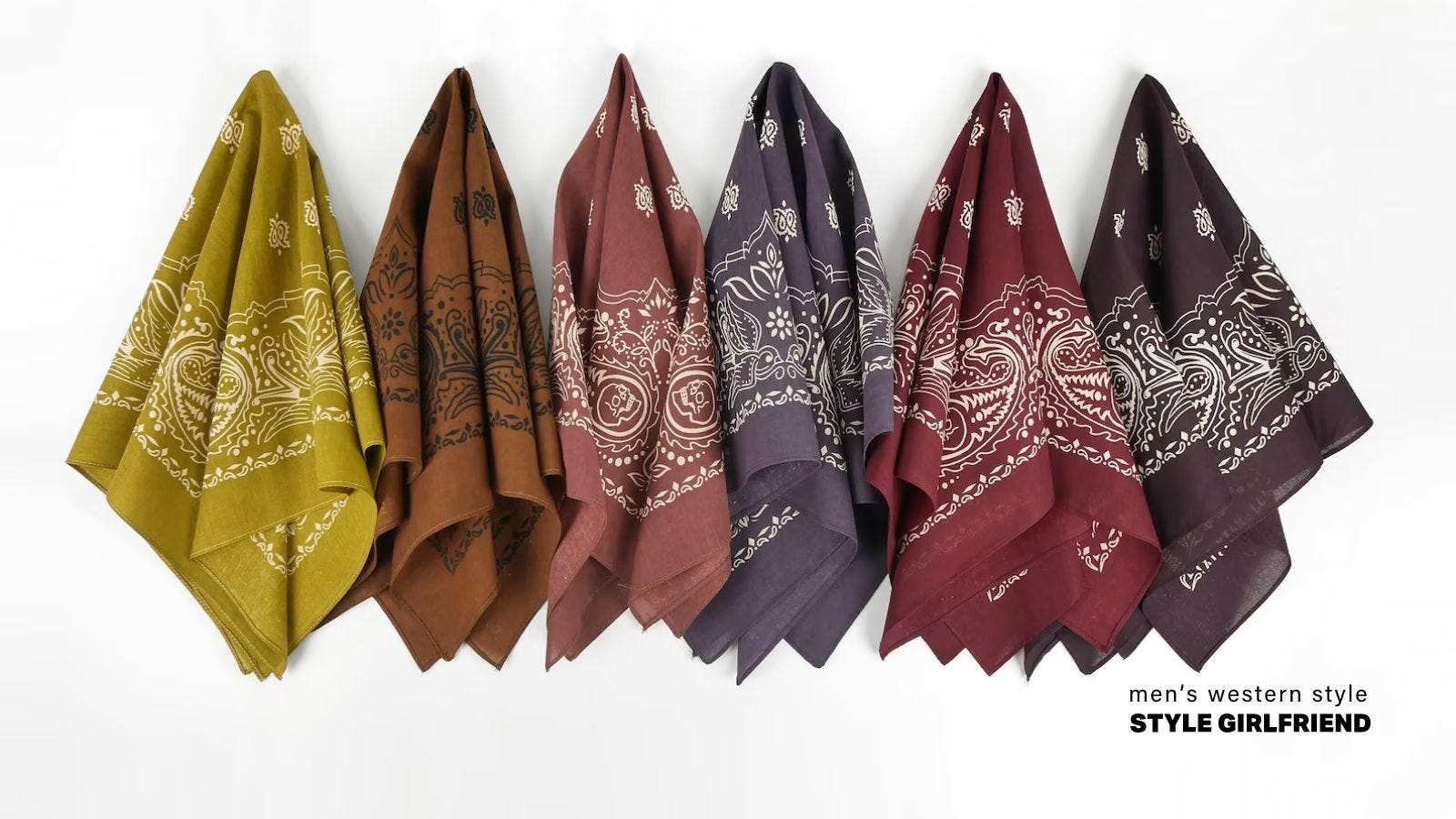 row of colorful patterned bandanas hanging on hooks. from left to right: yellow, dark brown, light brown, purple, red, brown