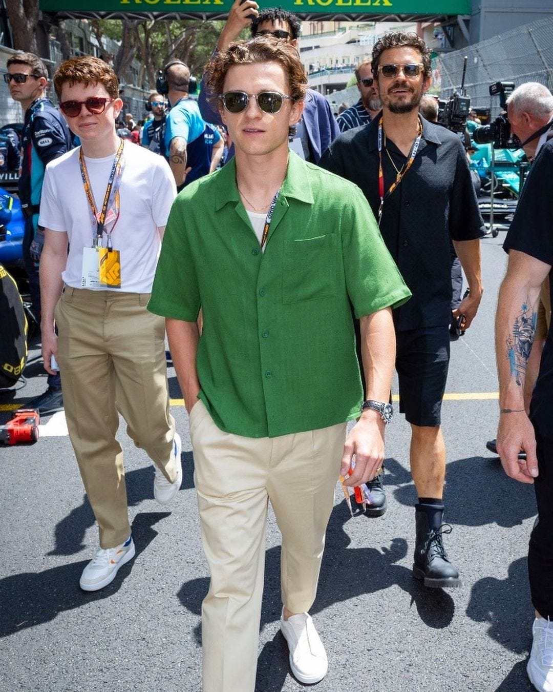 tom holland in a crowd, wearing a green shirt, khaki pants, and white sneakers