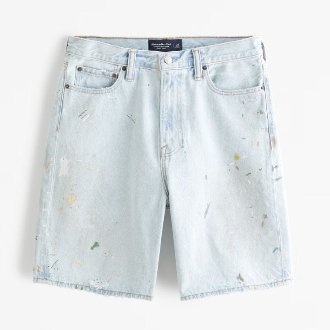Flat lay image of lightly washed denim shorts splattered with paint