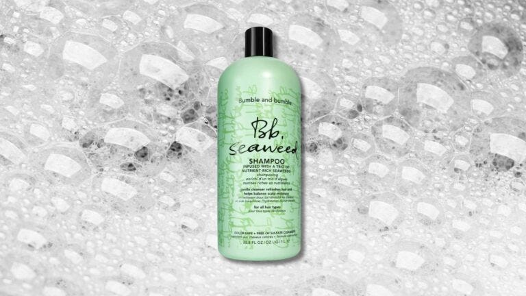 bottle of shampoo in a green container set against a background of soapy bubbles
