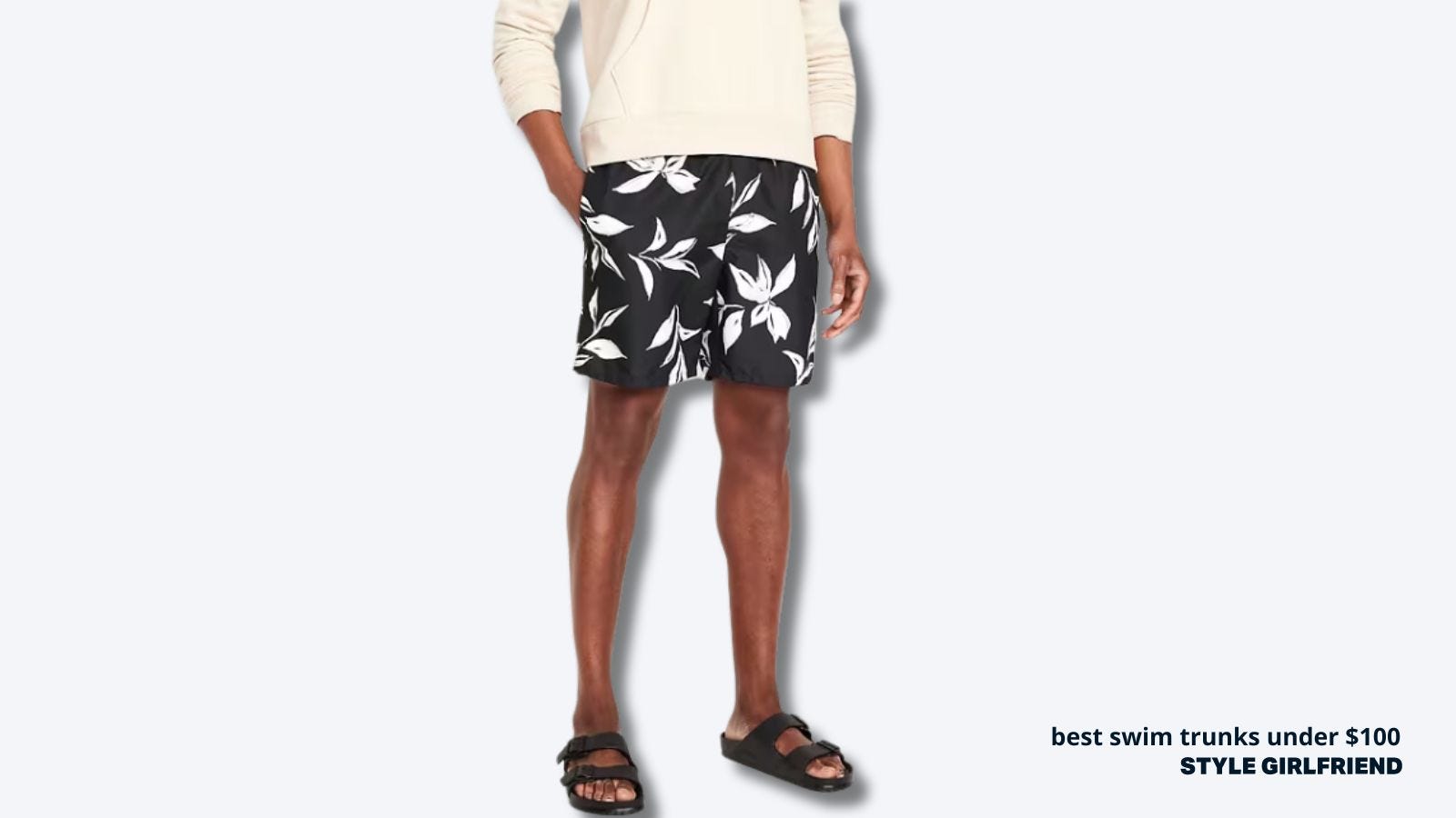 close up of a man wearing black and white floral print men's swim trunks with black sandals