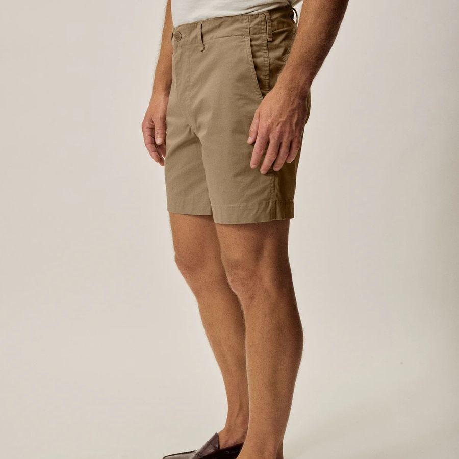 lower half of a man in tan chino shorts against a neutral background
