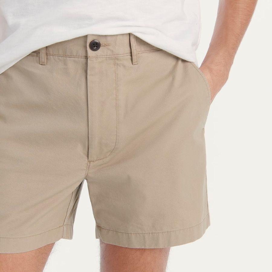 close-up of a man wearing khaki-colored chino shorts and a white t-shirt with his hand in his pocket