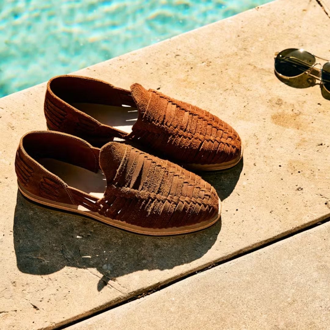 pair of huarache sandals positioned at the edge of a pool, a pair of sunglasses sits nearby