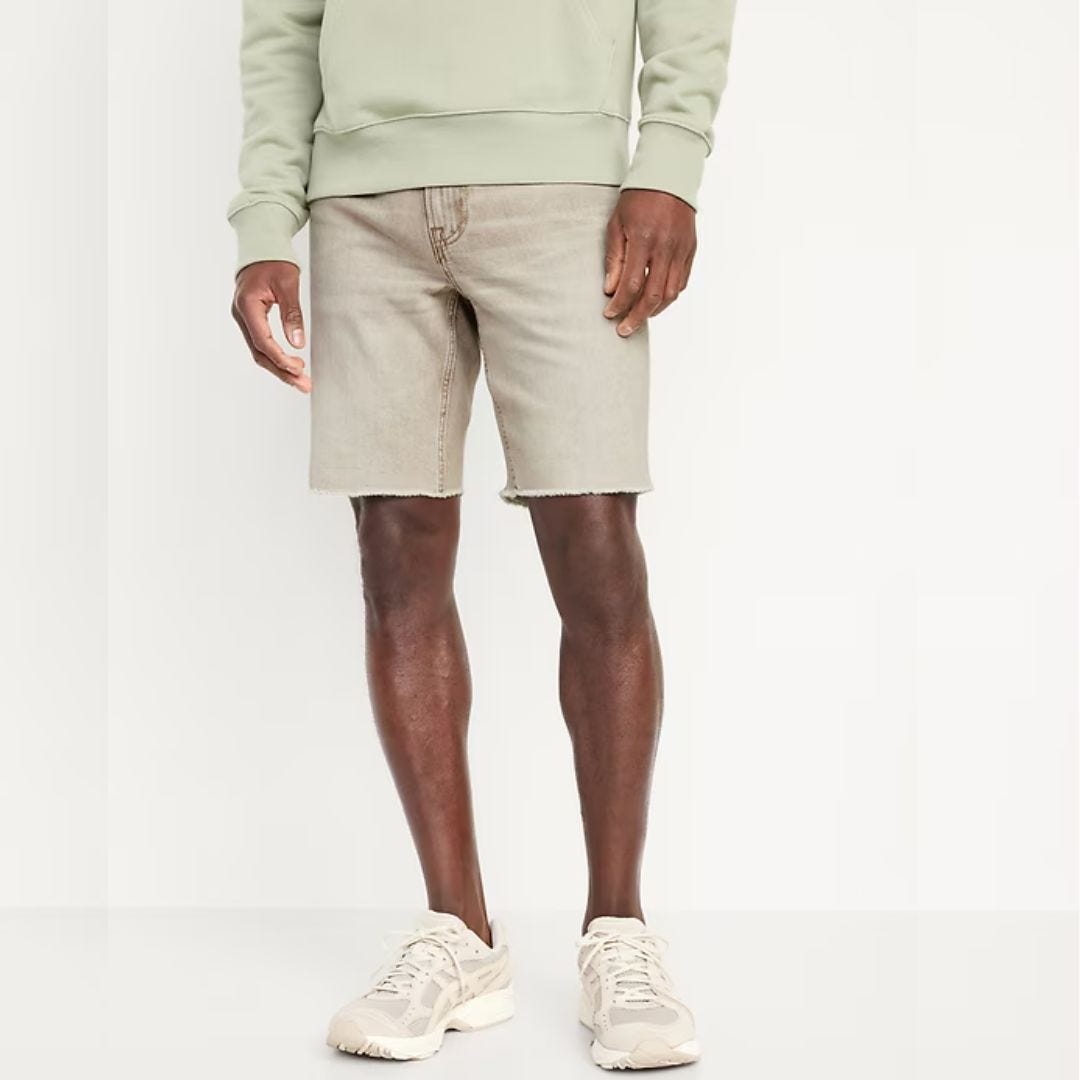 Image of a man wearing a mint sweatshirt, faded denim shorts and sneakers from the waist down