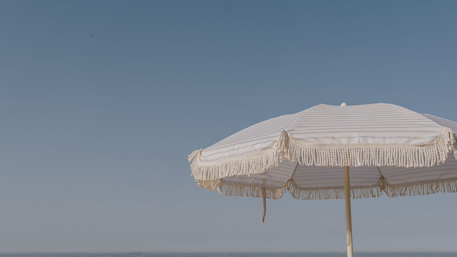 faded image of a beach umbrella against a blue sky