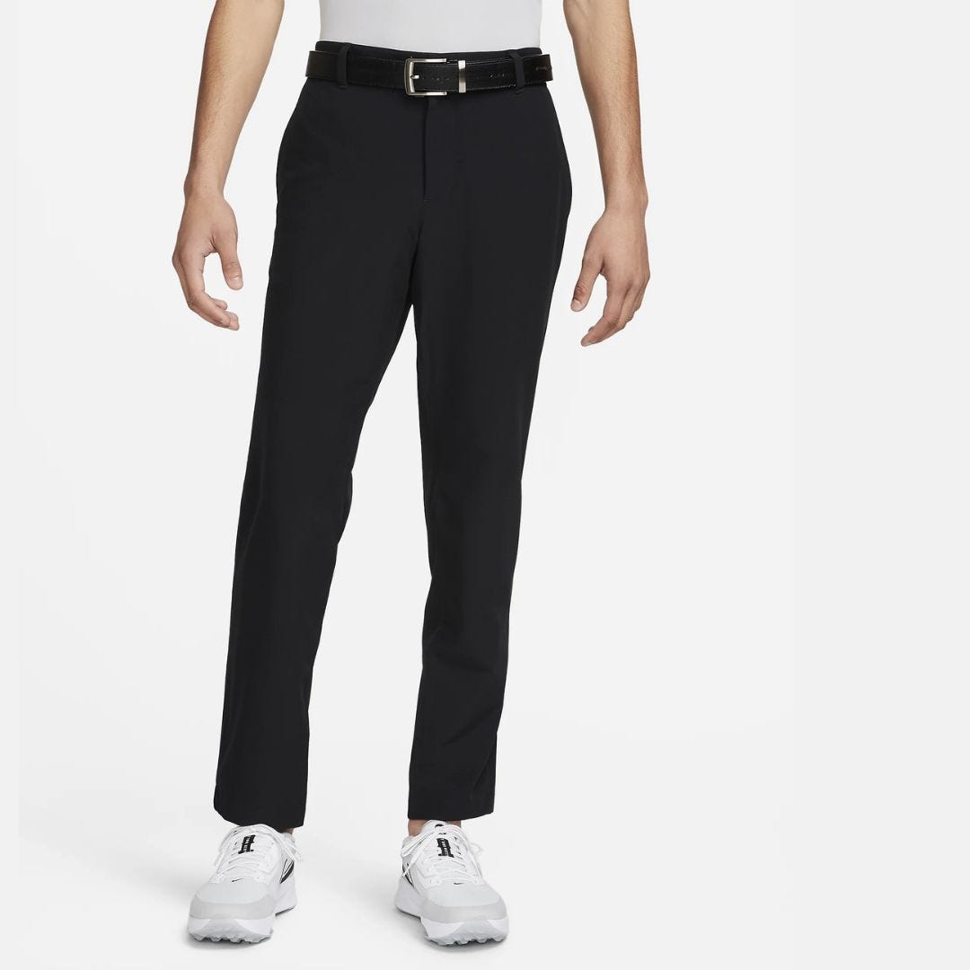 image of a man from the waist down wearing black golf pants with a black belt and white golf shoes