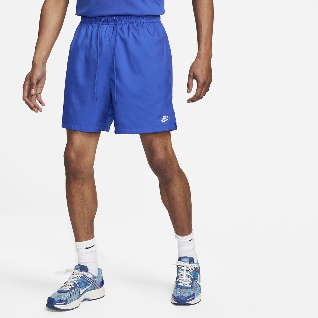 lower half of a man in blue nike sport shorts and blue sneakers