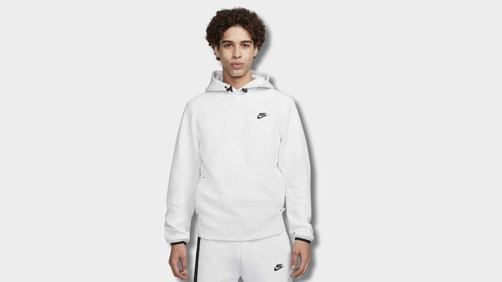 man from the waist up wearing a white hoodie with a black nike logo on the chest and black toggles at the neck