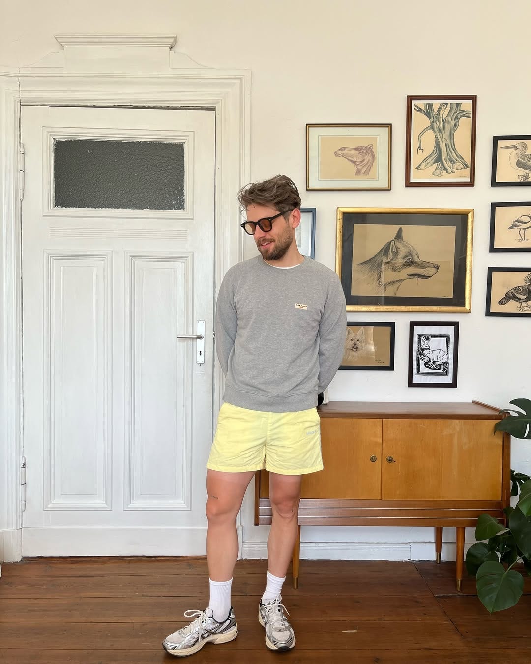 stylish man wearing a grey sweatshirt with butter yellow hybrid shorts and asics sneakers