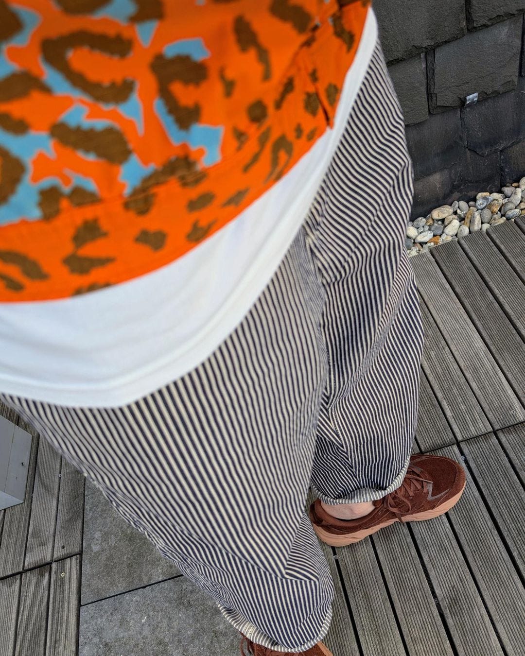 man wearing striped pants and an orange animal printed long-sleeve top