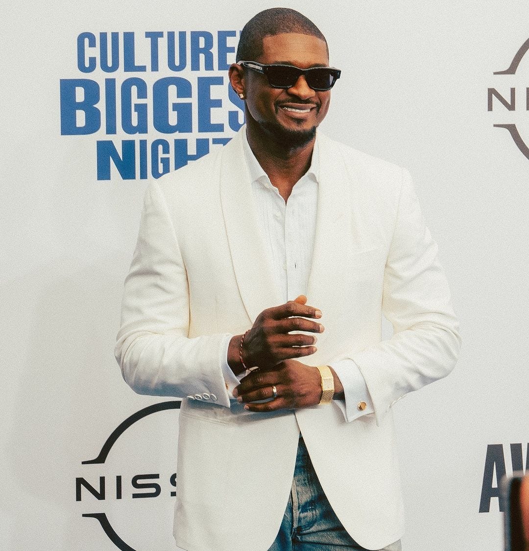 Usher at the BET Awards 2024 wearing a white tuxedo jacket, white shirt, and light rinse denim jeans