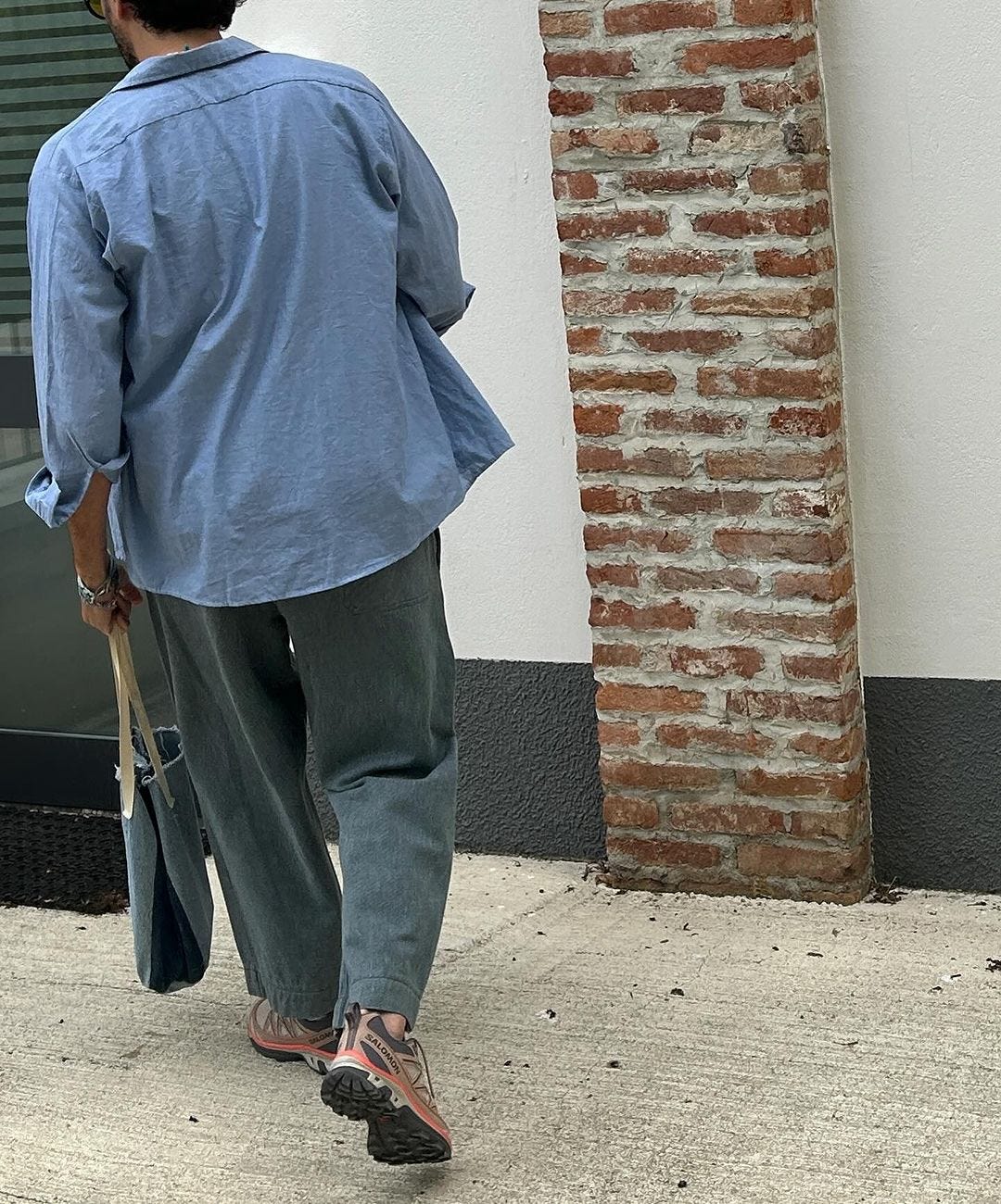 man from behind wearing a chambray shirt with wide legged jeans and sneakers