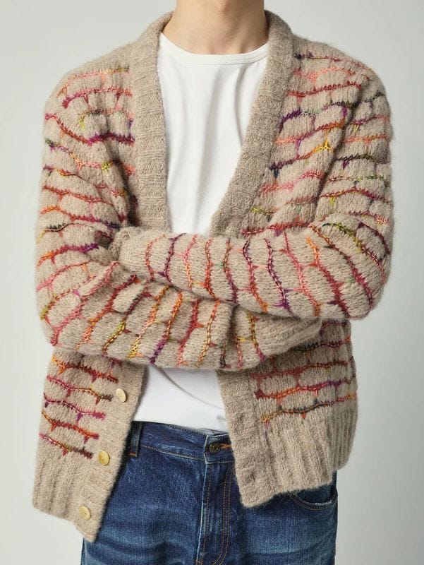 close-up of a man wearing a multi-color cardigan over a white t-shirt with blue jeans