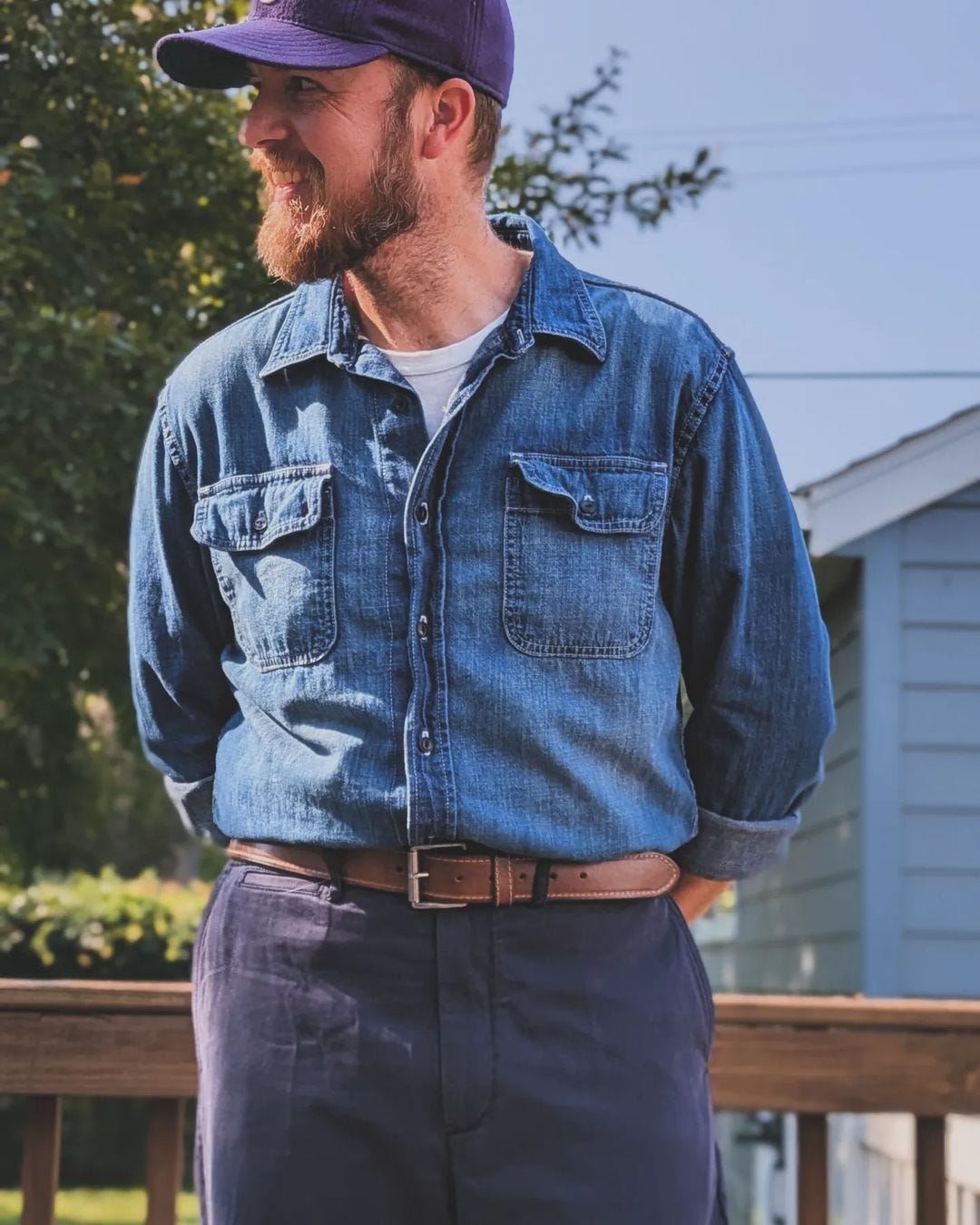 close-up of a man wearing a chambray button-down shirt with a brown belt and dark blue pants