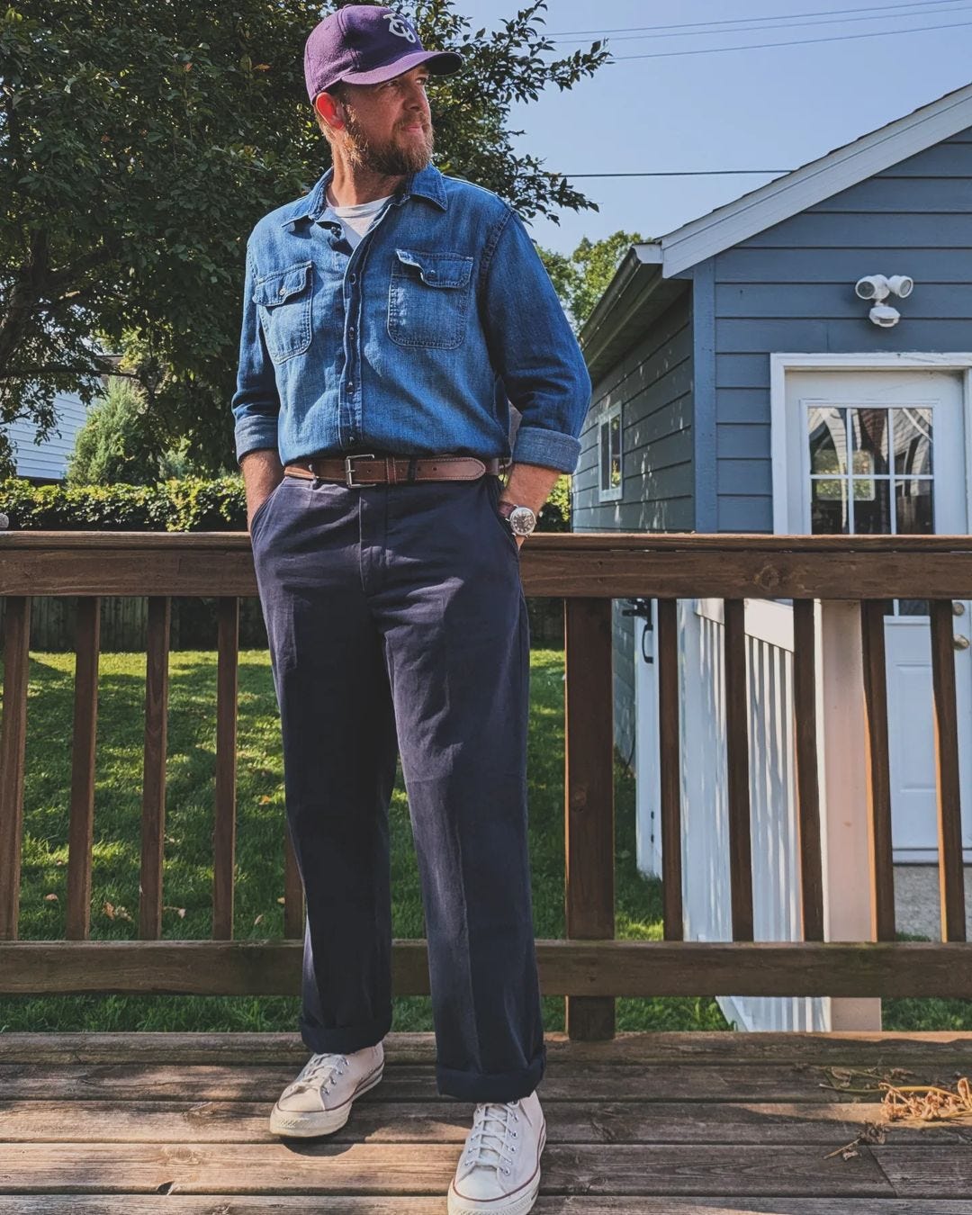 man wearing a dark blue chambray shirt with blue pants and a brown belt