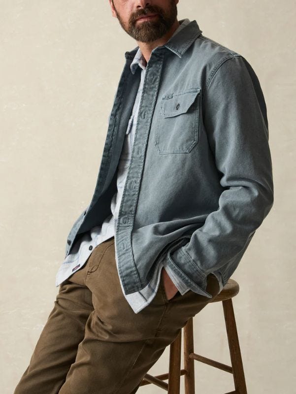 man sitting on a stool wearing a faded blue overshirt