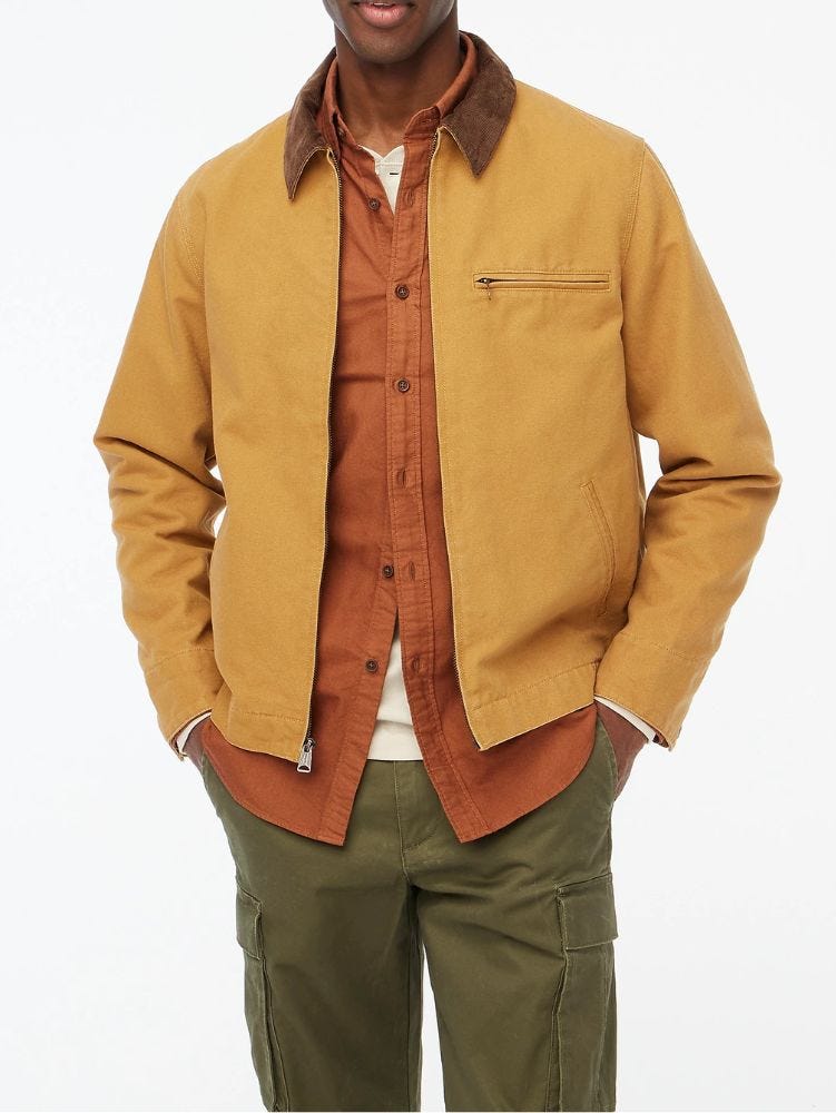 man from the neck down wearing a tan canvas work jacket over a red button down shirt and olive green pants