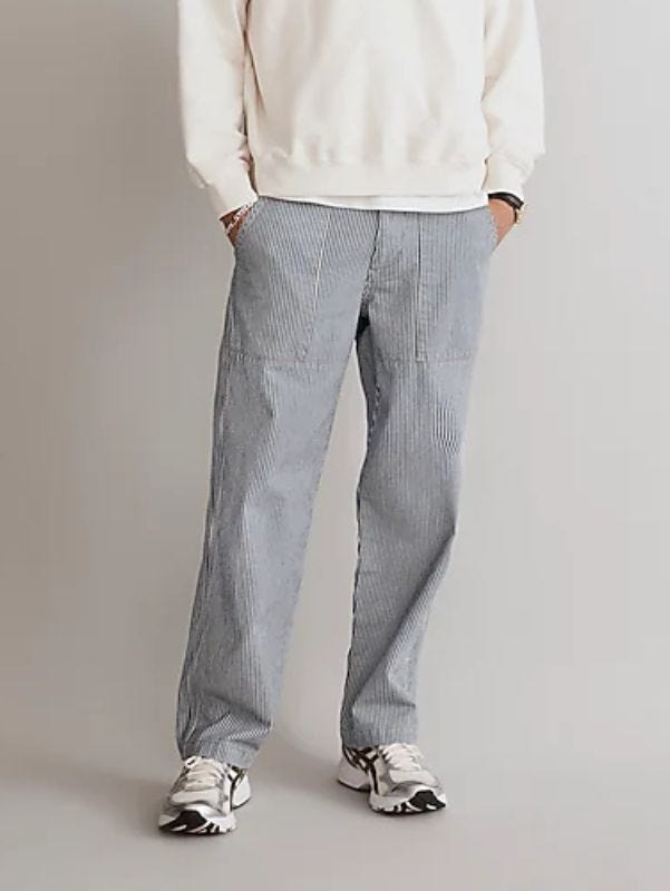 Man wearing train conductor striped baggy pants and cream sweatshirt from waist down