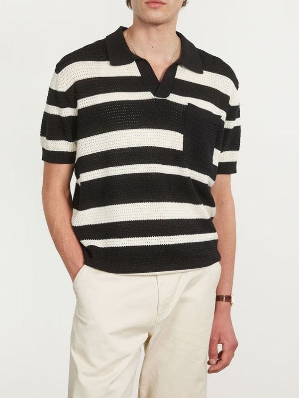 close-up of a man wearing a black and white striped knit polo with white trousers