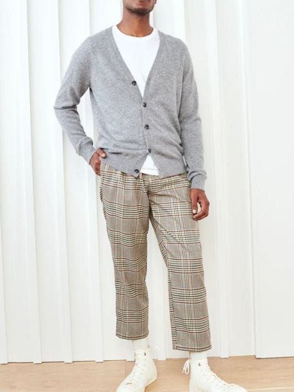 man from the neck down wearing a v-neck grey cardigan over a white crewneck t-shirt with plaid pants and sneakers