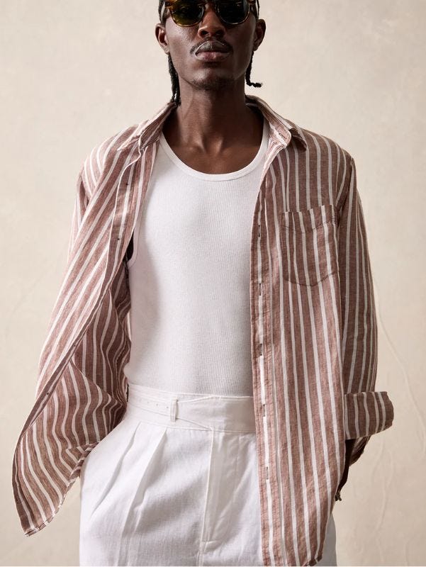 close-up of a man wearing a brown and white striped long-sleeve shirt over a white undershirt with white trousers