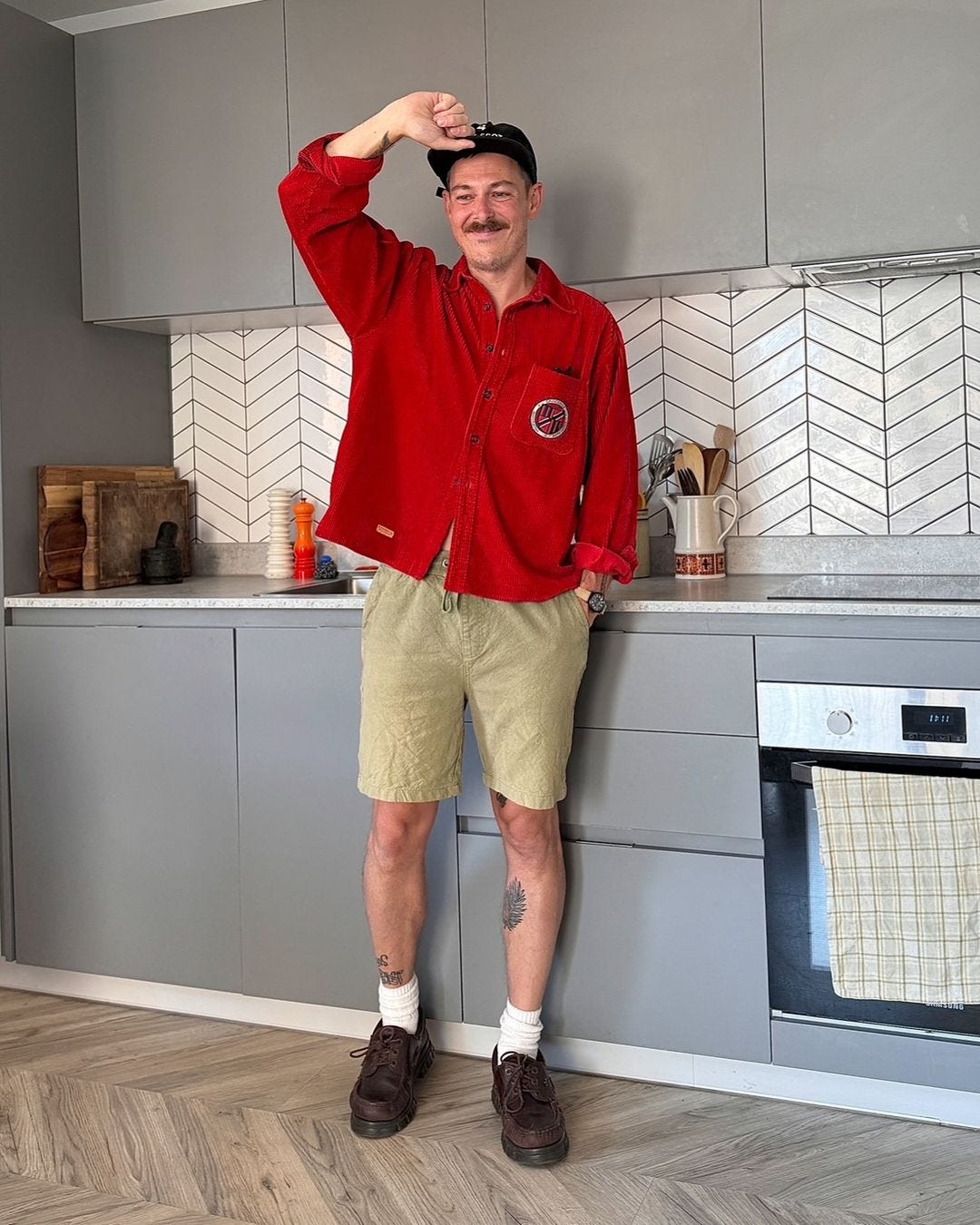 Man wearing red tie shirt, khaki shorts, brown shoes and white socks