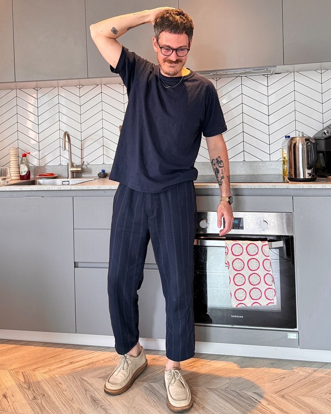 Man wearing dark striped pants and matching t-shirt standing in kitchen