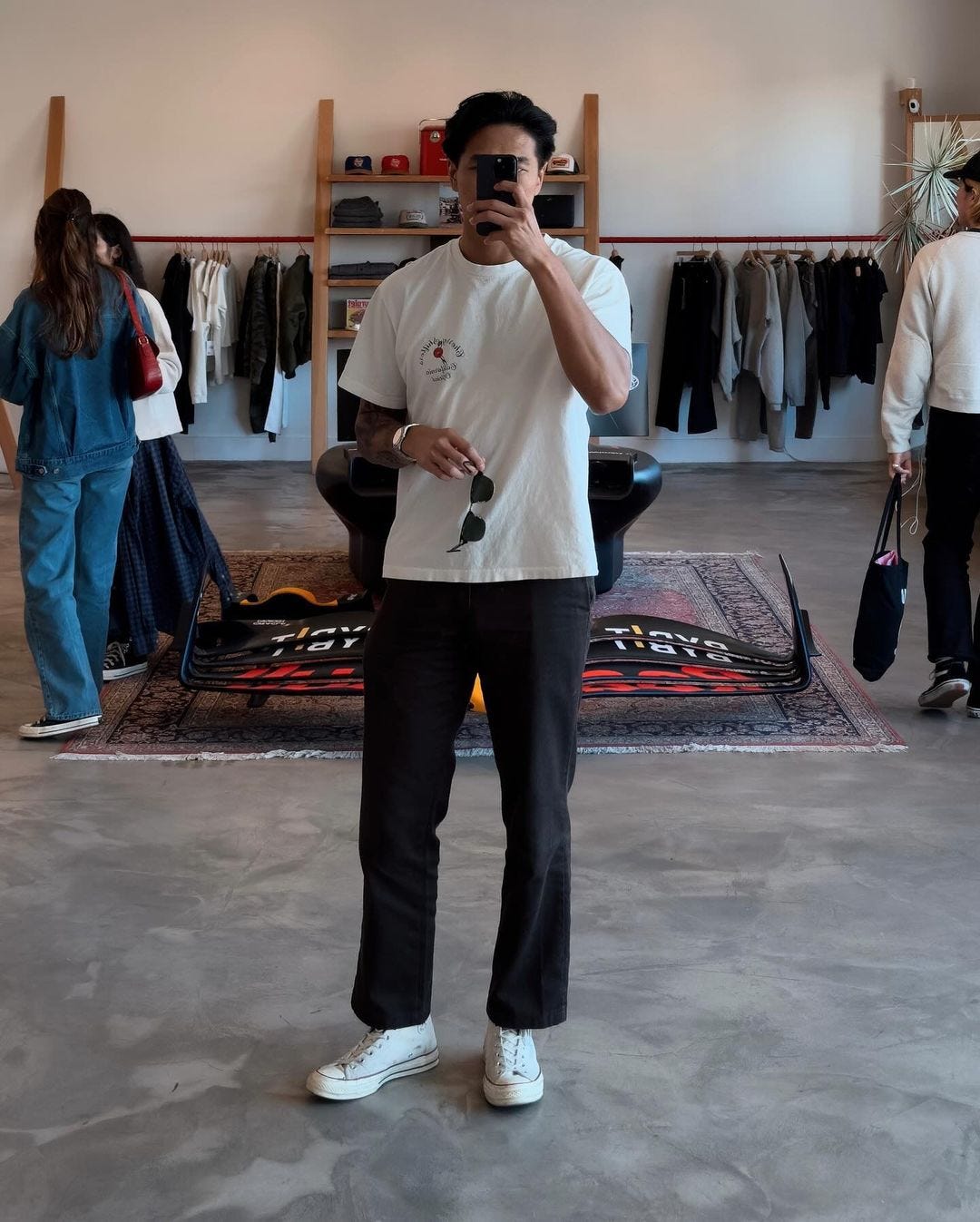 a man in a store taking a selfie, wearing a white t-shirt and dark-colored dickies 874 workwear pants, and high top converse