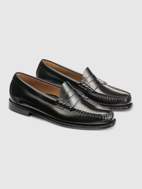 black leather penny loafers against a grey background