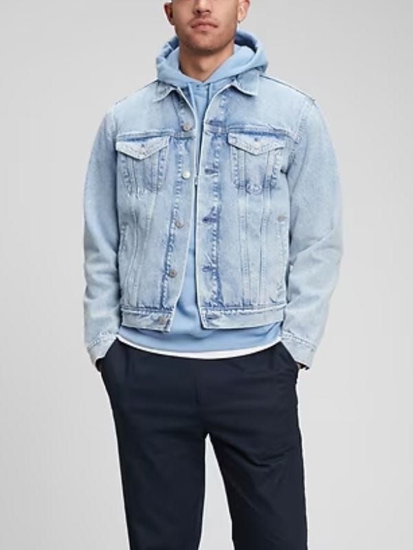 man from the neck down wearing a light denim jacket over a light blue hoodie sewatshirt with dark pants