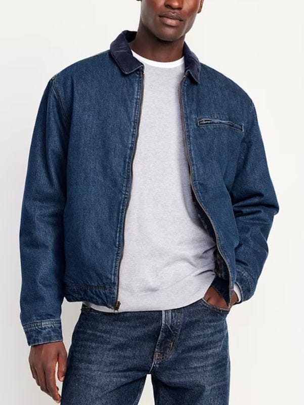 man from the neck down wearing a dark denim workwar jacket over a grey shirt with dark jeans