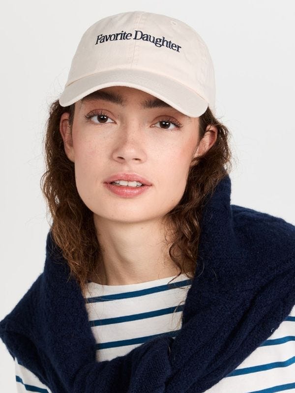 woman wearing white baseball cap with "favorite daughter" embroidered in blue across the front