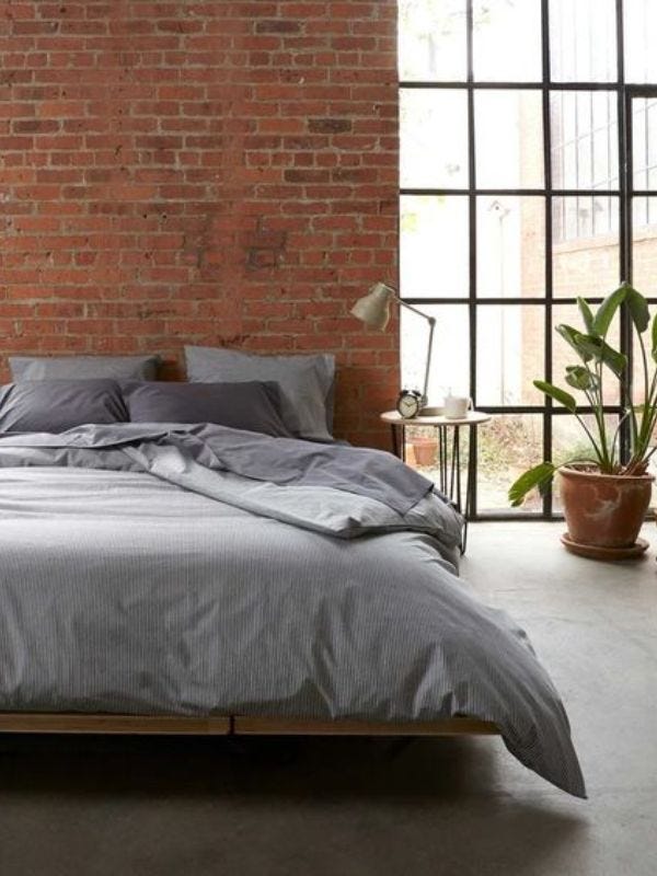 stylish loft apartment with platform bed in front of brick wall and large window