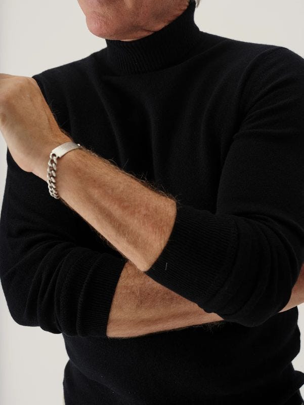 close-up of a man wearing a black turtleneck with a silver bracelet on his wrist