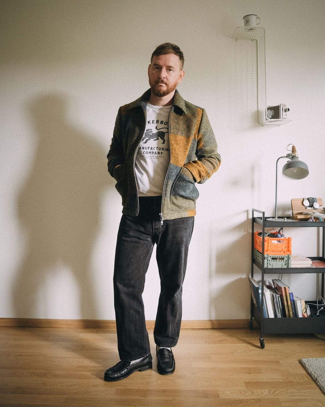 man wearing the NN07 jacket from "The Bear" with black jeans, a graphic tee, and black loafers