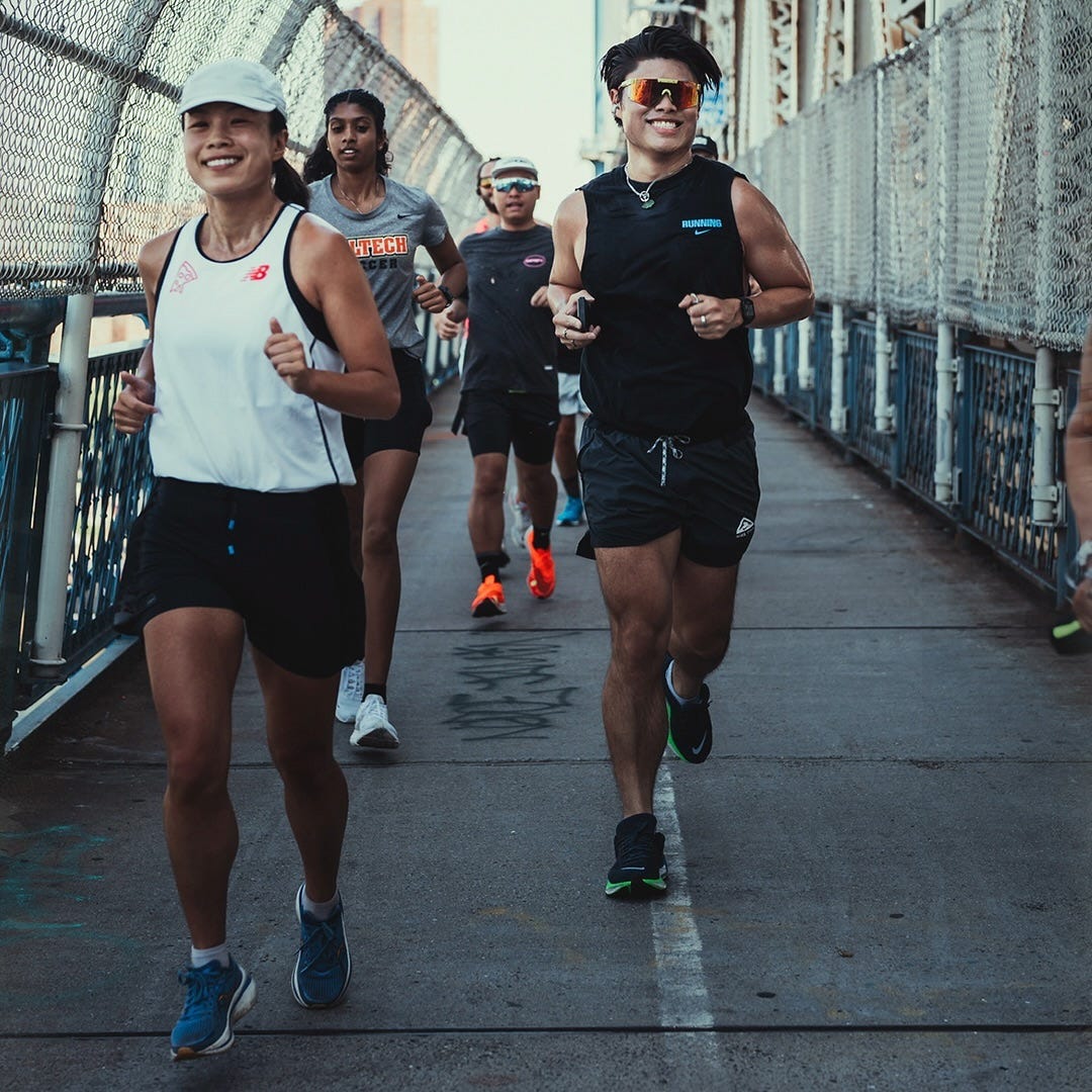 A group of smiling young runners crossing a bridge