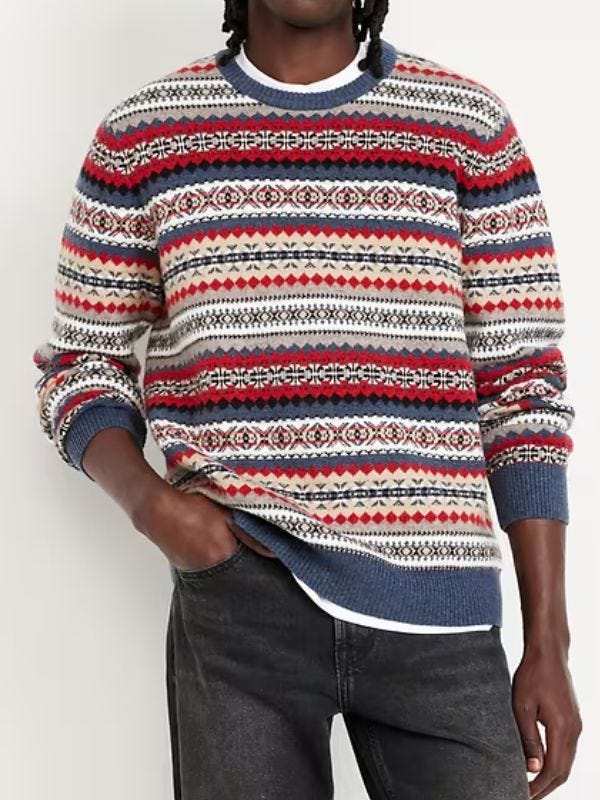 man from the neck down wearing a blue and red Fair Isle swater with black jeans